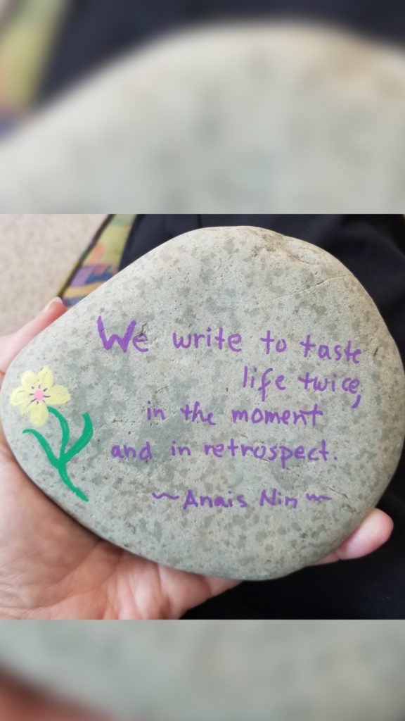 Dr. J. holds a decorative rock with a Anais Nin Quote. "We write to taste life twice, in the moment and in retrospect."